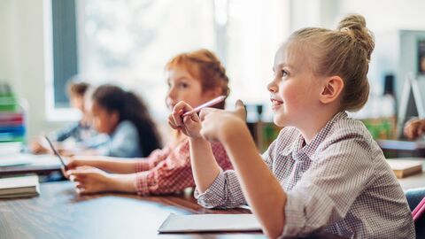Kinder sitzen an einem Tisch und hören gespannt zu
