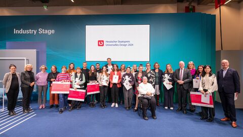 Über 20 Menschen stehen nebeneinander und halten ihre Auszeichnungen hoch.