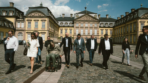 Eine Gruppe Menschen vor einem Schloss.